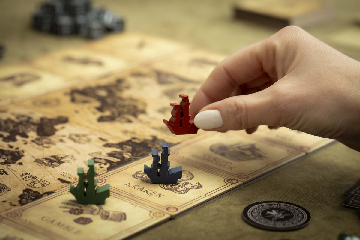 A hand moving a red wooden ship across the map tiles