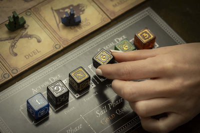 A hand placing a die on the dice board next to the map tiles