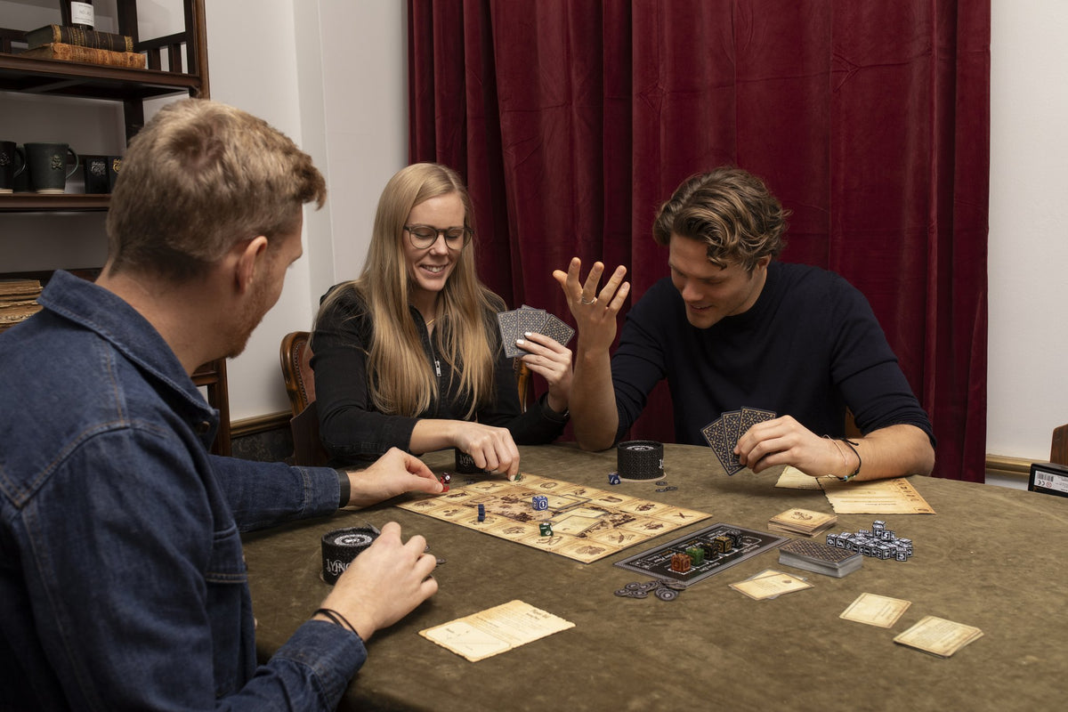 Three friends laughing and bluffing over a game of Lying Pirates
